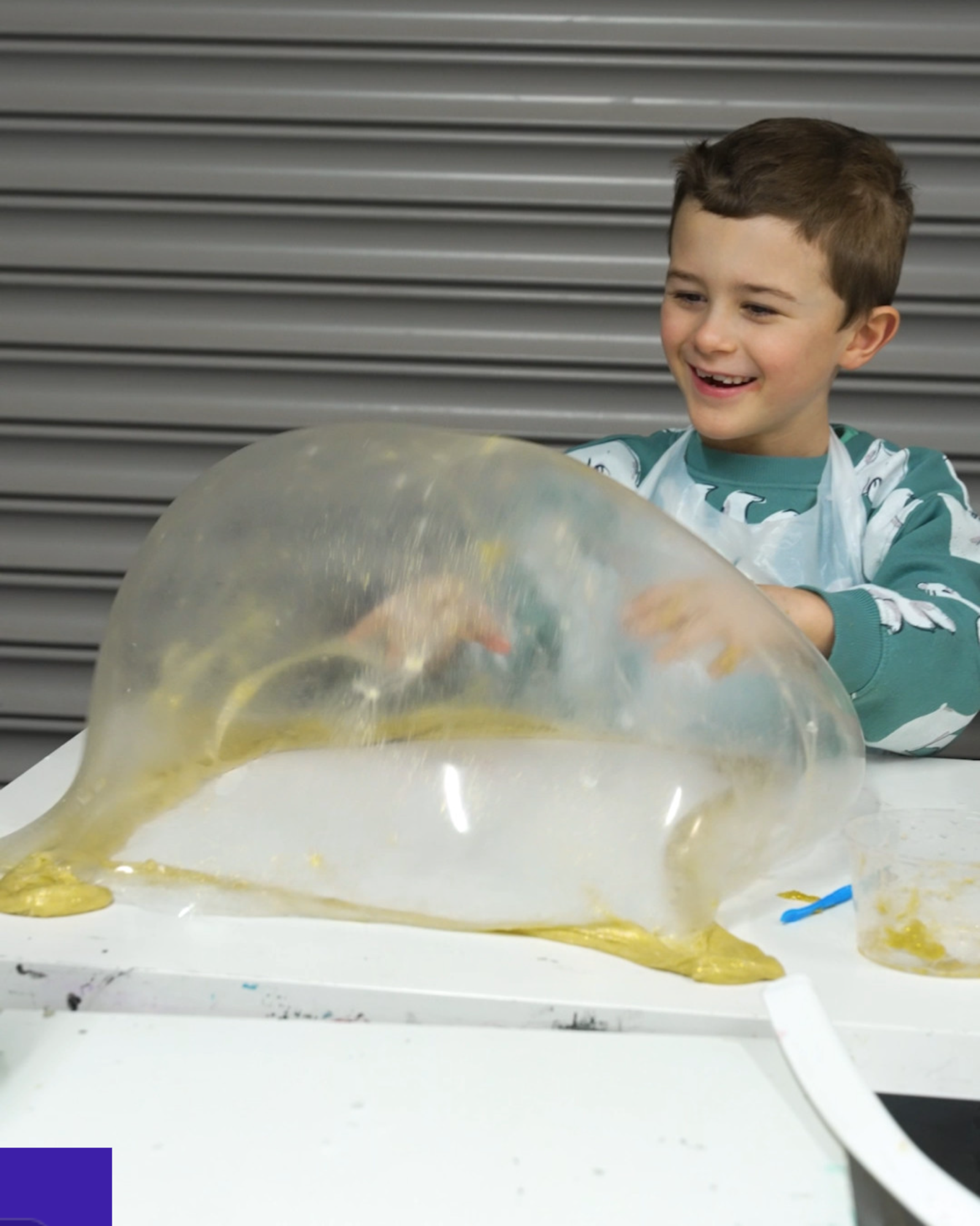 Child laughing while playing with a giant slime bubble